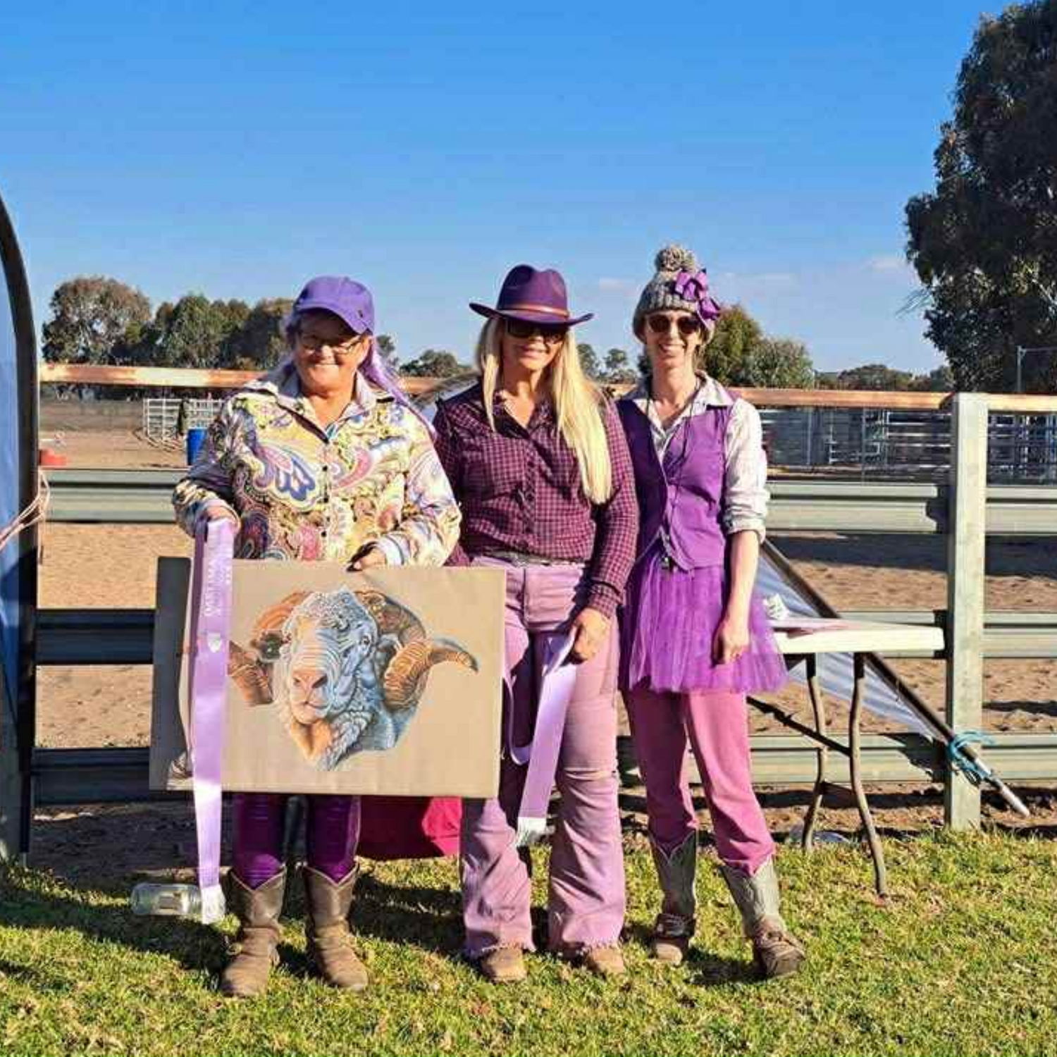 Three women in rural attire standing outdoors with a hay runner ram print